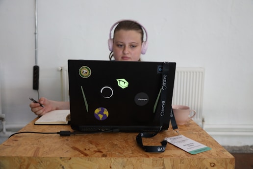 A focused student working at a desk with colorful planners and a laptop.
