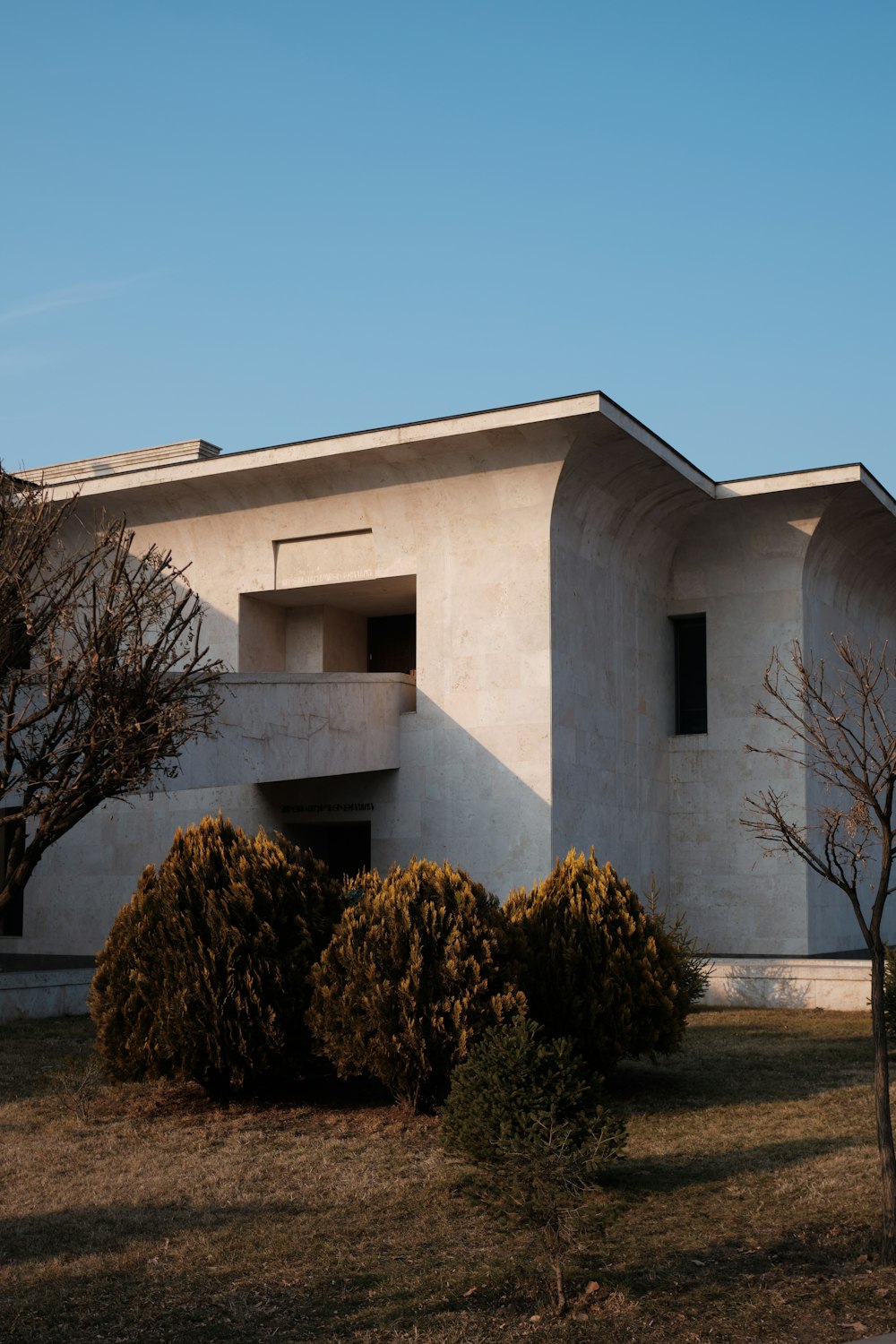 a white building with trees and bushes in front of it