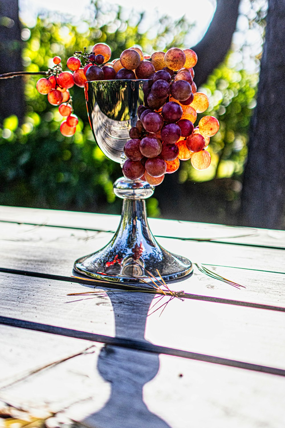 a glass filled with grapes sitting on top of a wooden table