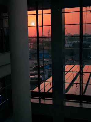 A sunset view through large windows of a modern luxury home interior.