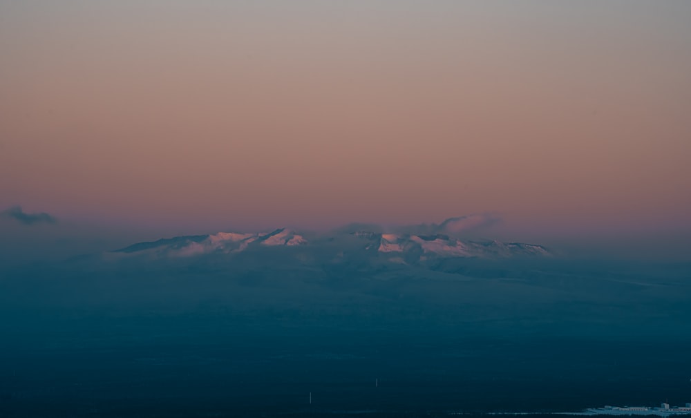 a view of a mountain with a pink sky in the background