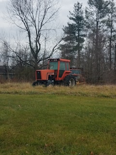 A well-maintained red tractor parked in a sunny field, ready for work.