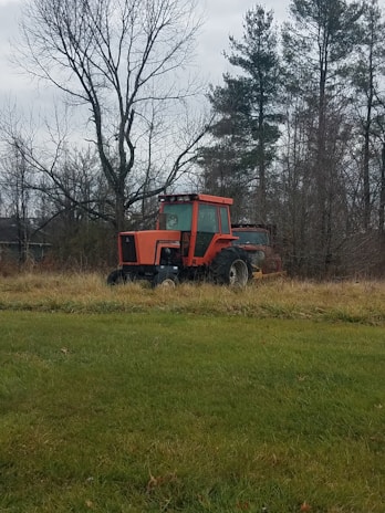 A well-maintained red tractor parked in a sunny field, ready for work.