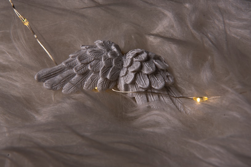 Softly glowing angel wings illuminated against a serene grey background.
