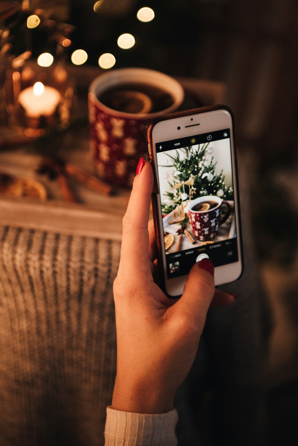 a woman taking a picture of a christmas tree