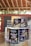 Several cans of flavored coffee, including charcoal and sea salt varieties, are arranged on a wooden table. The packaging features vibrant and colorful designs with cartoon characters. A box in the background displays more coffee cans, and some blurred text appears on a wall.