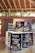 Several cans of flavored coffee, including charcoal and sea salt varieties, are arranged on a wooden table. The packaging features vibrant and colorful designs with cartoon characters. A box in the background displays more coffee cans, and some blurred text appears on a wall.