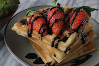 A top-down view of a waffle with melting chocolate and sliced strawberries arranged artistically.