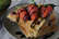 A close-up photo of a golden waffle topped with fresh strawberries, chocolate drizzle, and a scoop of vanilla ice cream on a rustic wooden table.