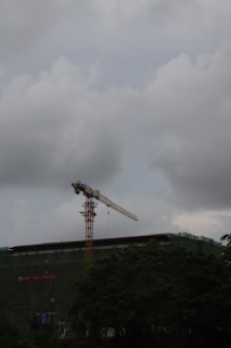 A construction site with scaffolding and a bright yellow crane against a clear blue sky.