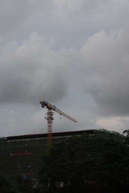 A construction site with scaffolding and a bright yellow crane against a clear blue sky.