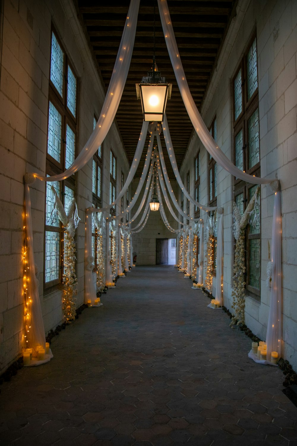 a long hallway decorated with white ribbon and lights