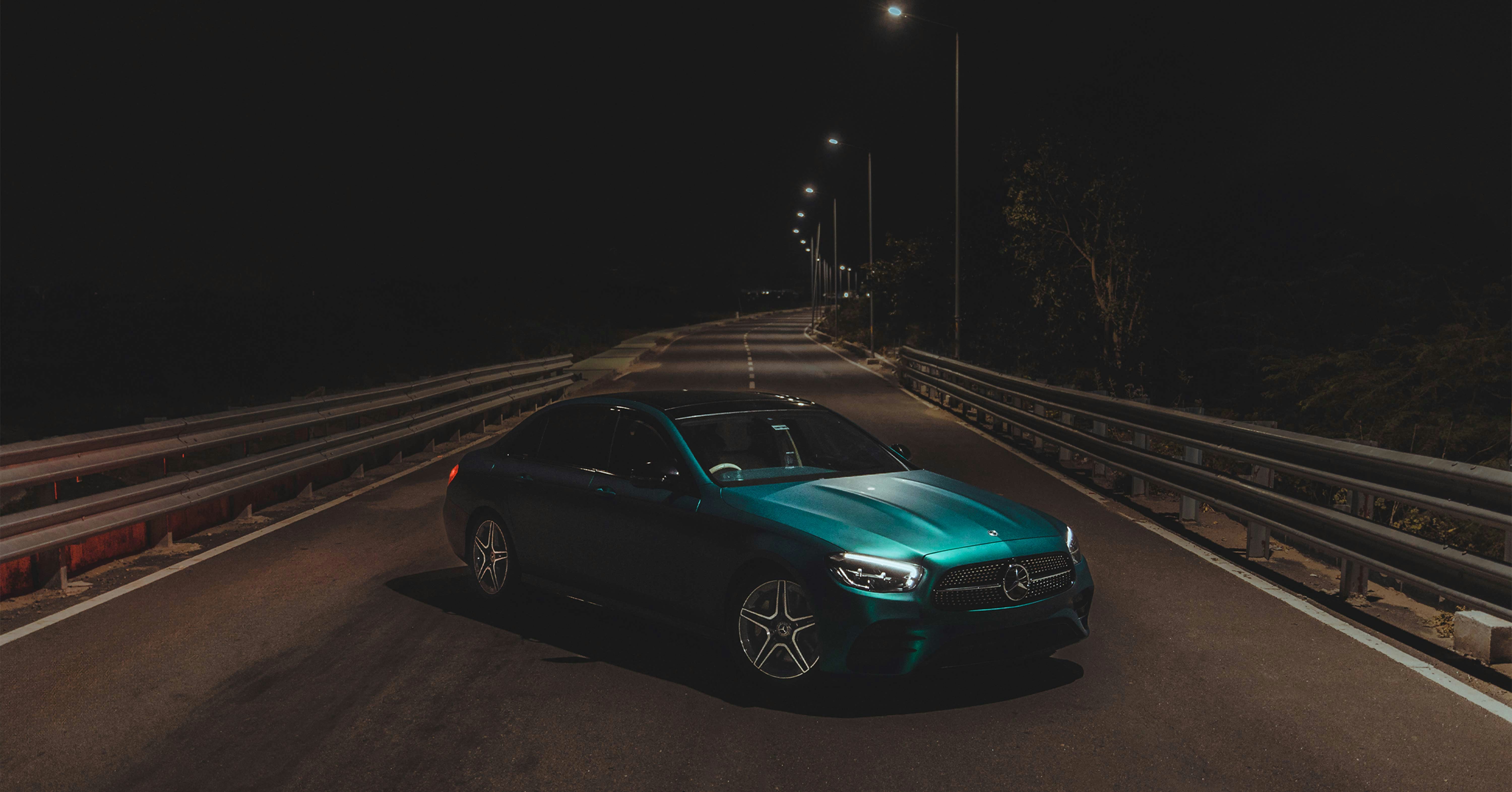 a blue car driving down a road at night