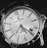 A close-up of an analog wristwatch with bold markers and intricate detailing on the dial. The watch face is elegant, has a date window, and features a combination of numerals and indices. The brand name and other inscriptions are visible, surrounded by a polished metal case.