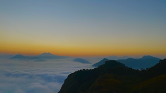 A serene landscape featuring a misty mountain range at dawn.