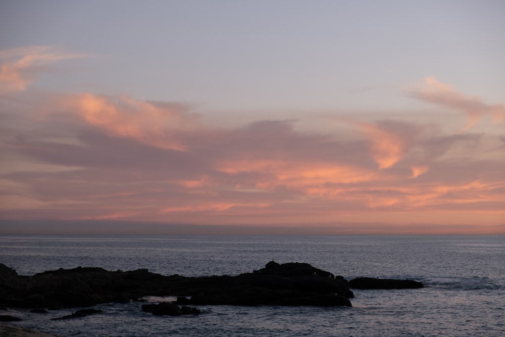 a sunset view of the ocean with clouds in the sky