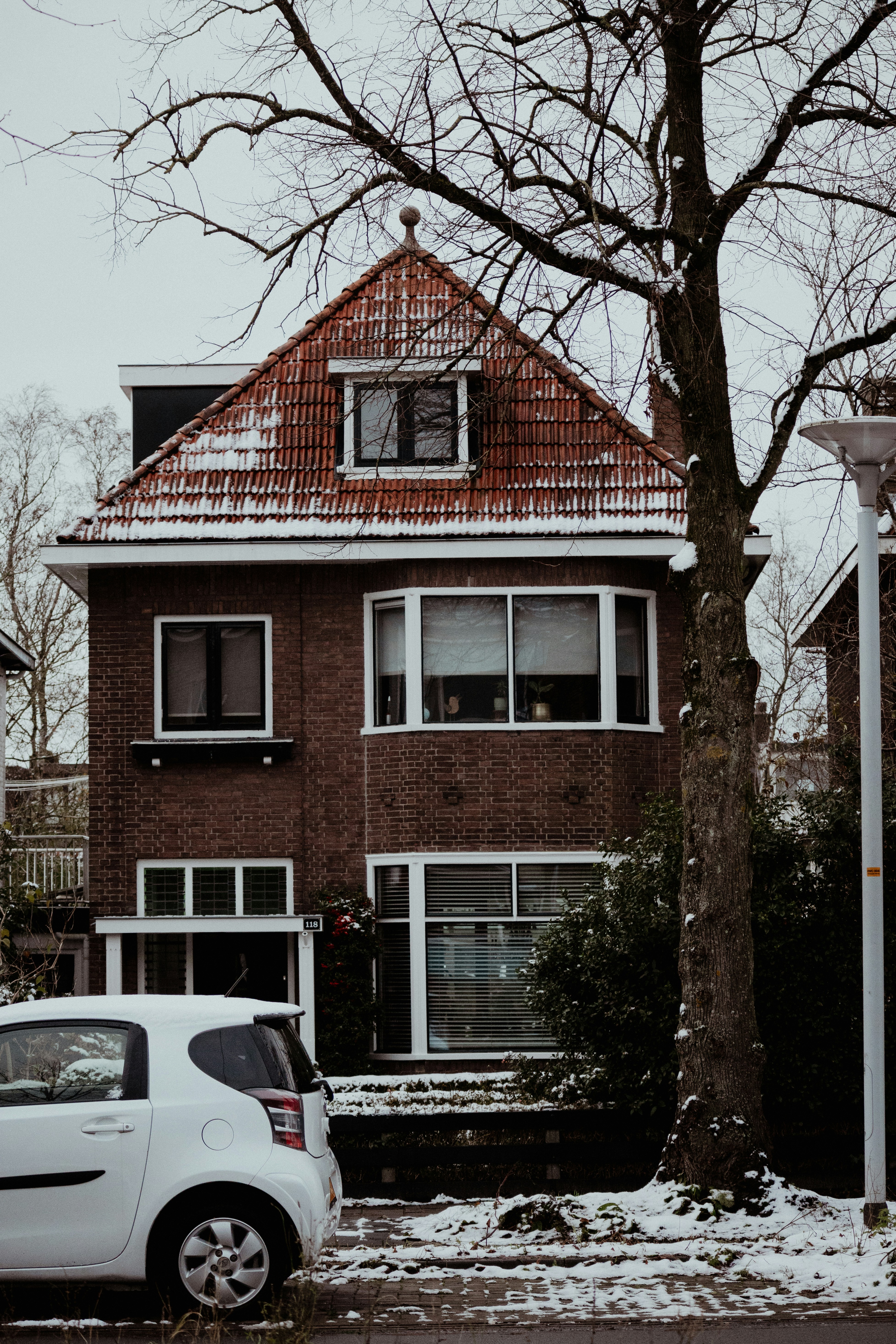 a white car parked in front of a red brick house