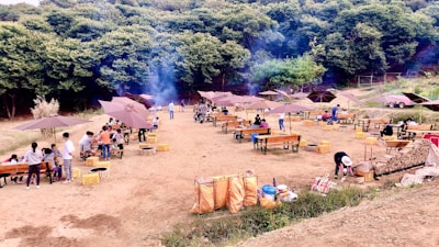 Group of friends enjoying a barbecue outside a wooden cabin surrounded by green trees.