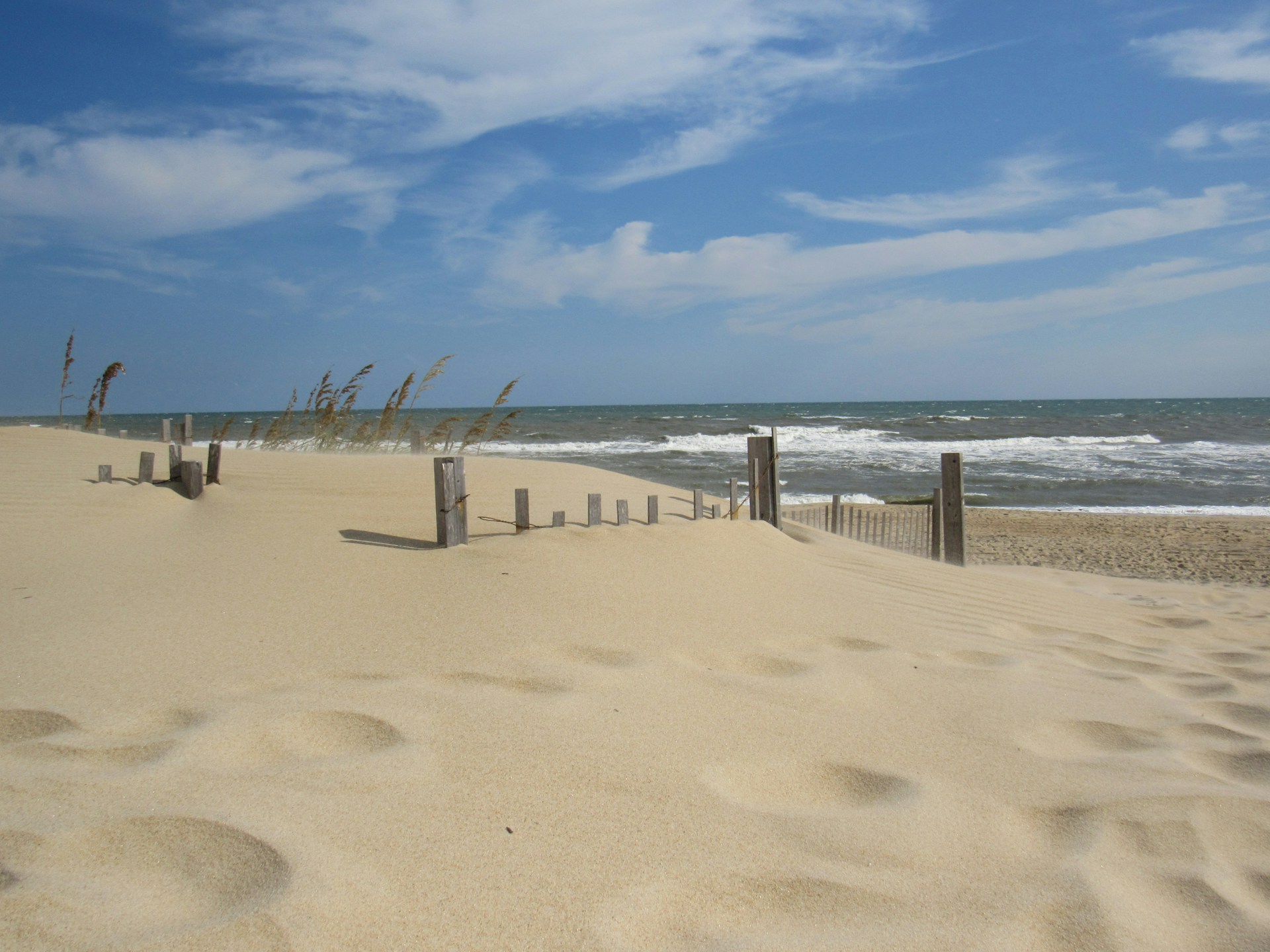 a sandy beach next to the ocean under a blue sky