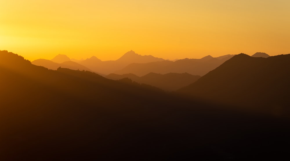 the sun is setting over a mountain range