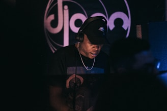 An artist wearing headphones, focused in a dimly lit studio with neon accents.