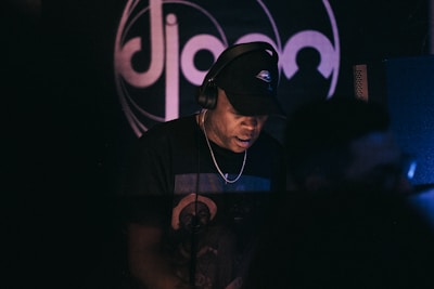 An artist wearing headphones, focused in a dimly lit studio with neon accents.