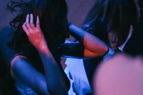 Close-up of a female hairstylist’s hands expertly sectioning long hair under dramatic stage lighting.