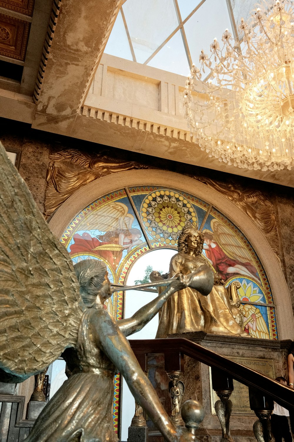 a statue of a woman holding a tray in a room with a chandelier