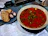 A warm, inviting bowl of traditional Romanian ciorbă served with fresh parsley on a rustic wooden table.