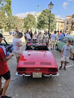 A group of car enthusiasts gathered around a vintage convertible at a car show.