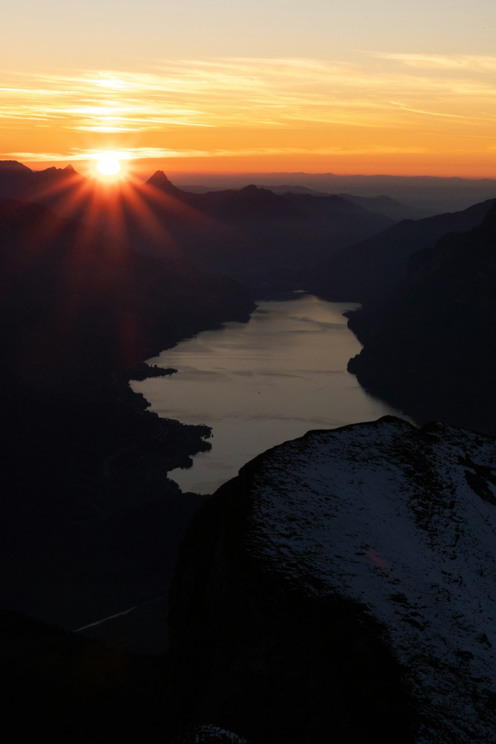 the sun is setting over a lake in the mountains