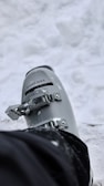 Close-up of durable ski boots with reinforced soles, dusted lightly with fresh snow.