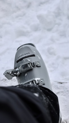 Close-up of durable ski boots with reinforced soles, dusted lightly with fresh snow.