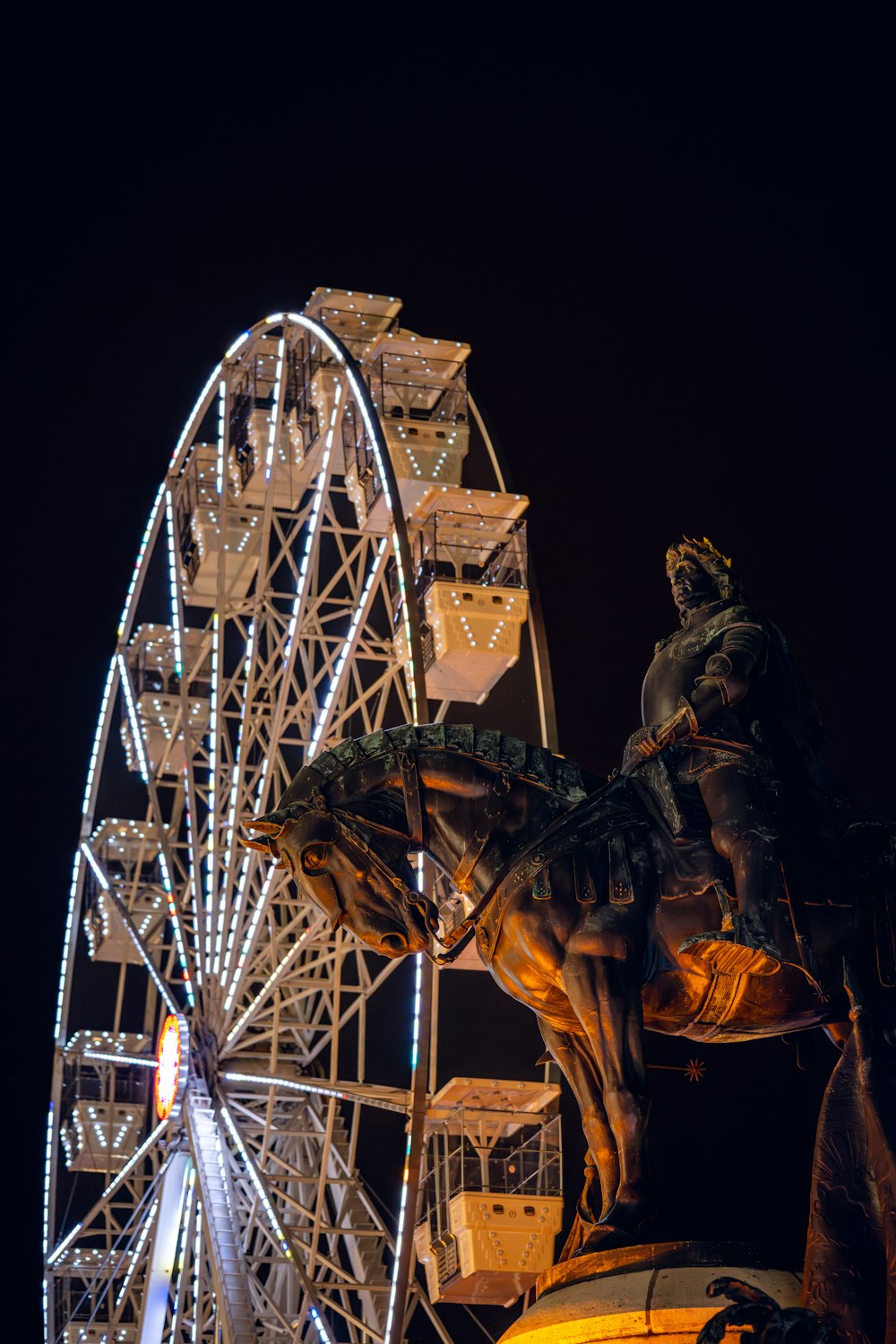 a statue of a man riding a horse next to a ferris wheel