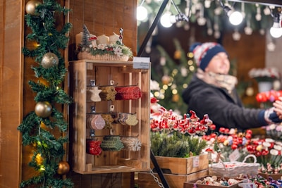 A warmly lit Christmas market stall decorated with subtle dark green and deep red ornaments.