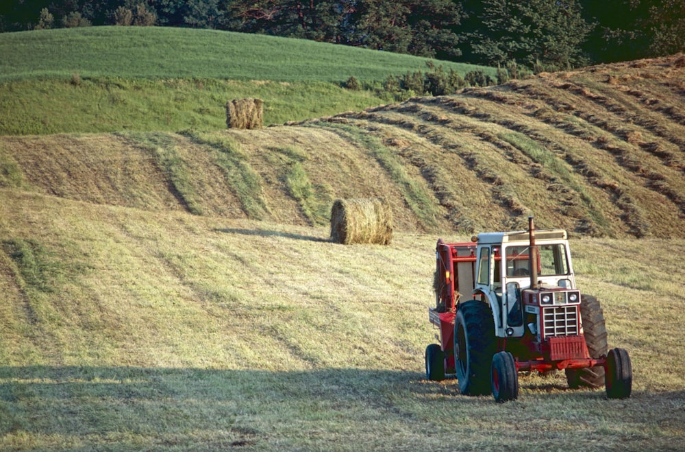 a tractor in a field with bales of hay in the background