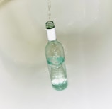 A hand filling a recycled glass bottle with freshly filtered water.