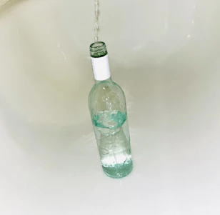 Fresh, clear water pouring into a transparent Sipko branded bottle with droplets on its surface reflecting purity.