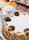 A variety of desserts including a layered cake covered in sliced almonds and decorated with chocolate-covered strawberries. Nearby are fruit tarts topped with fresh fruits like kiwi and strawberries as well as a meringue-topped pie.