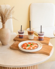 a table with a plate of pizza and two cups of coffee