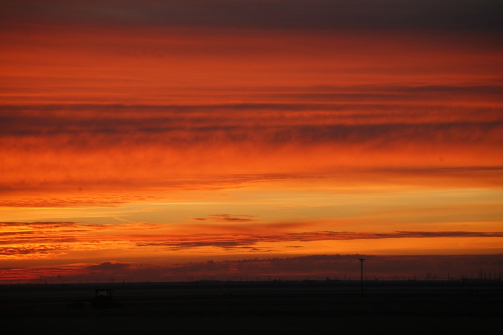 a red and yellow sky with clouds in the distance