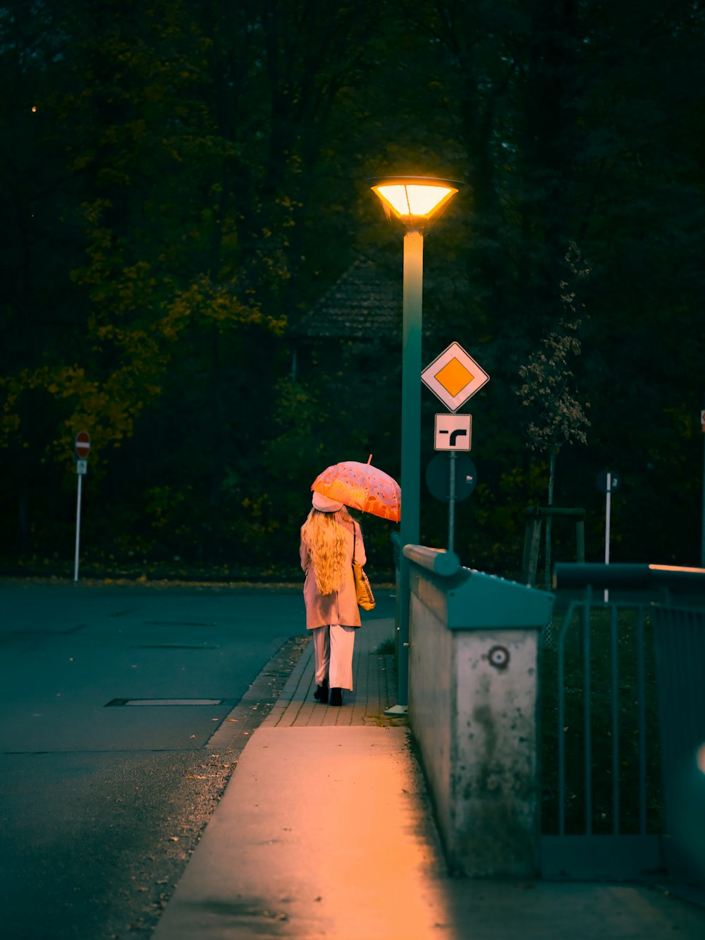 a woman walking down a sidewalk holding a pink umbrella