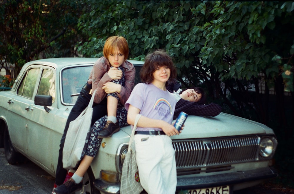 two people sitting on the hood of a car