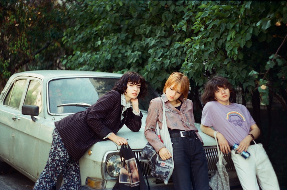 a group of young women standing next to a car