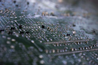 Close-up of a vibrant green FR-4 PCB with intricate copper traces under bright lighting.