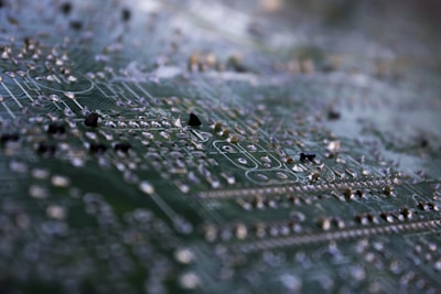 Close-up of a technician performing microsoldering on a drone circuit board under a microscope.