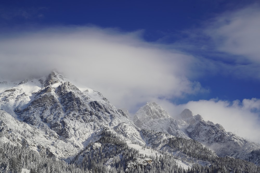 a mountain covered in snow under a cloudy blue sky