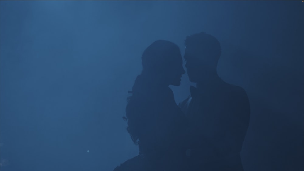 a silhouette of a man and a woman kissing in the dark