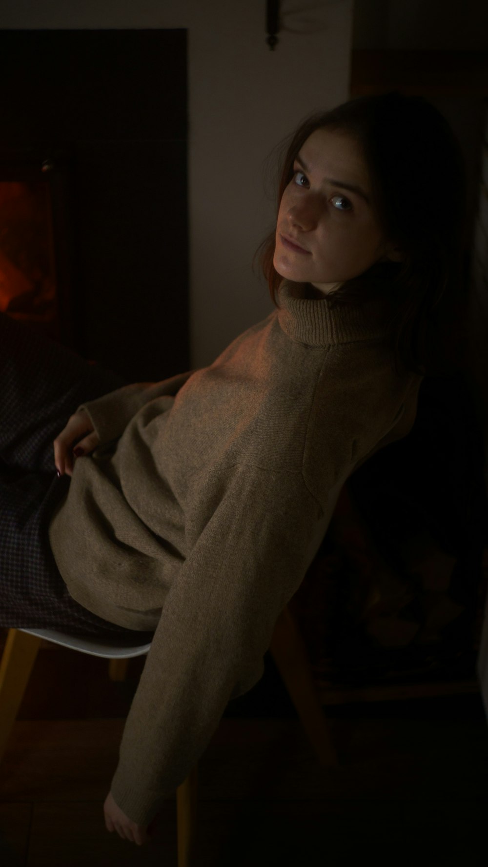 a woman sitting in a chair in front of a fire place