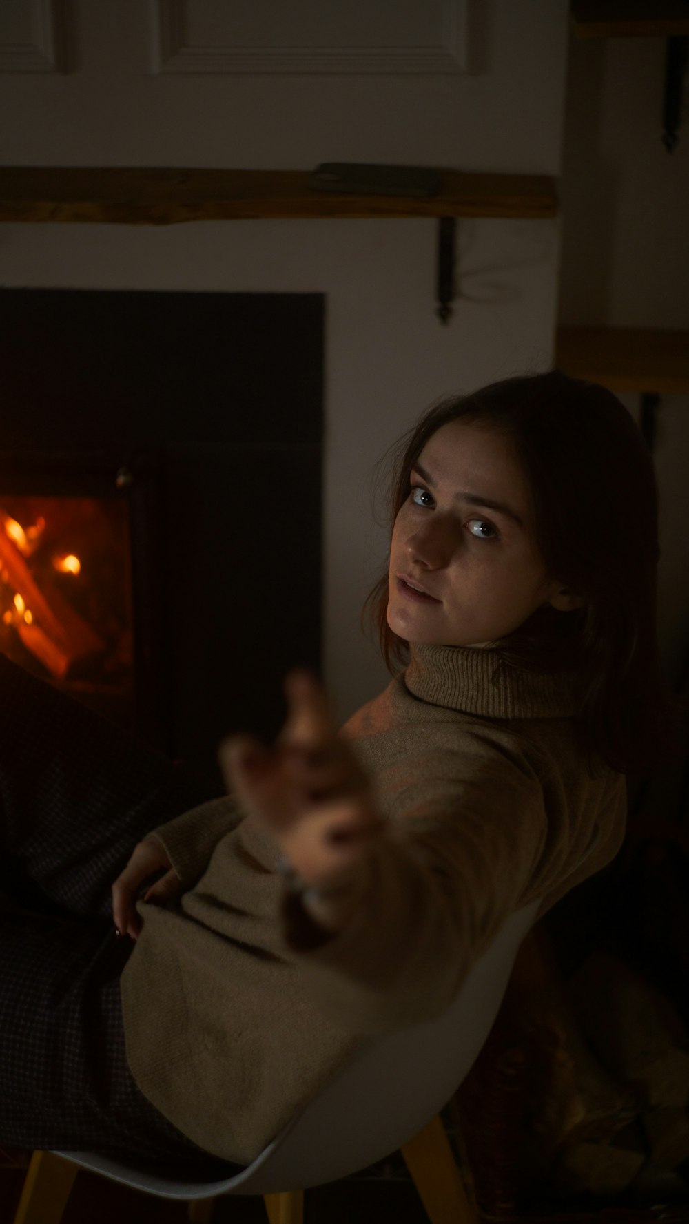 a woman sitting in a chair pointing at a fire